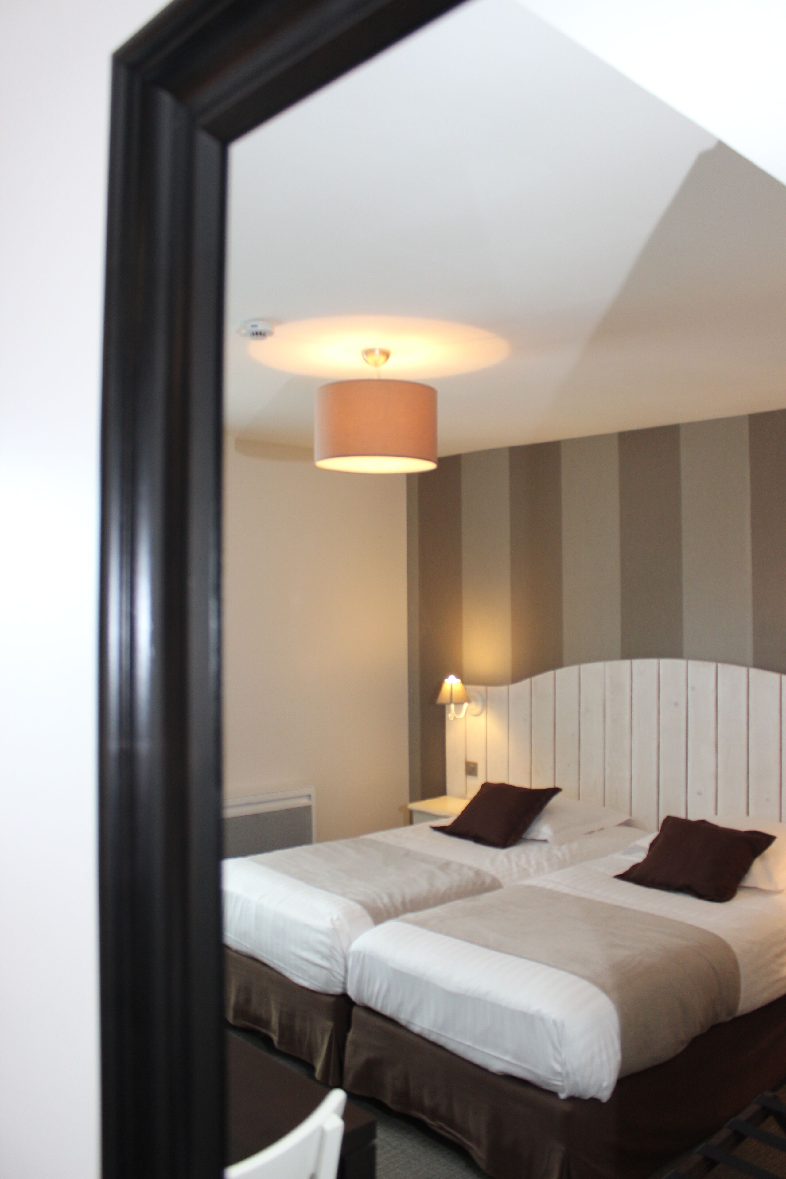 Ein Hotelzimmer mit zwei Betten, einem Kopfteil, einem Nachttisch und einer Lampe.