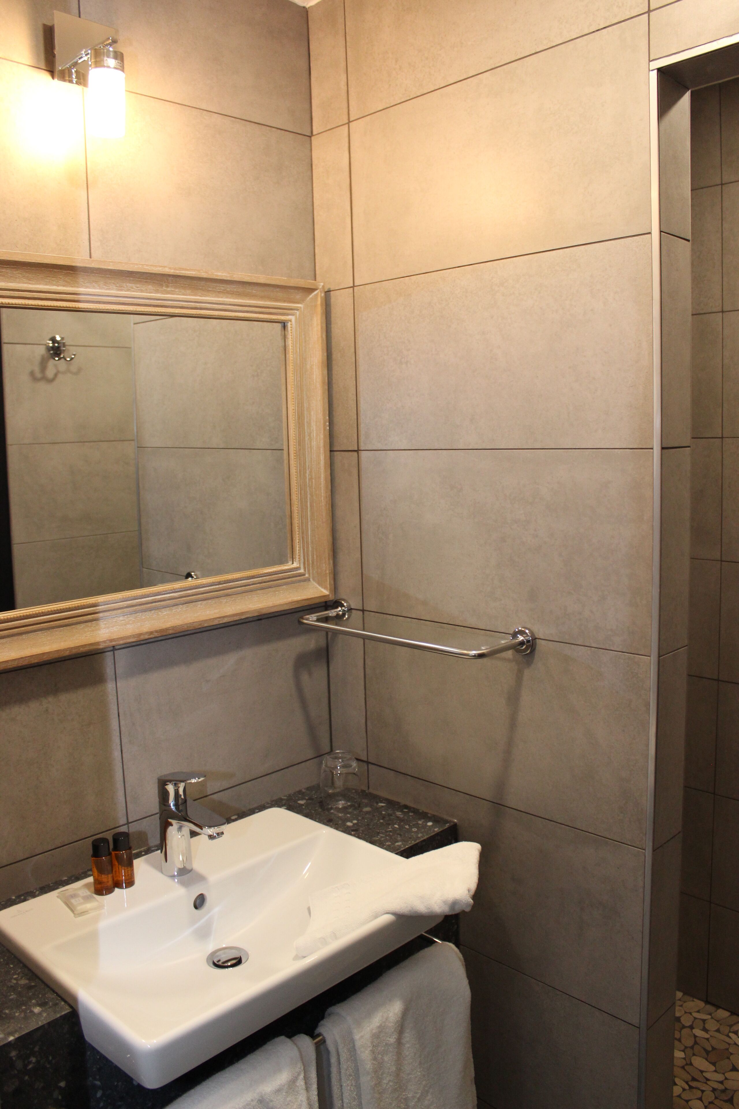 A bathroom with a white sink, a mirror, and a towel rack.