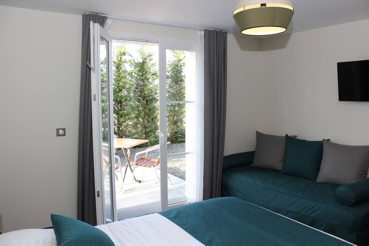 A hotel room with a bed, a sofa, a table, and a view of the outdoors.