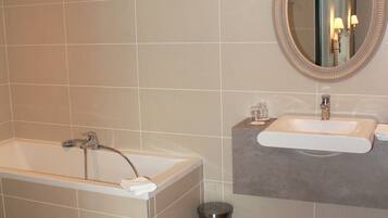 A modern bathroom with a bathtub, a sink, and a mirror.