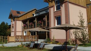 Een gebouw met twee verdiepingen, een balkon, terras en een tuin.