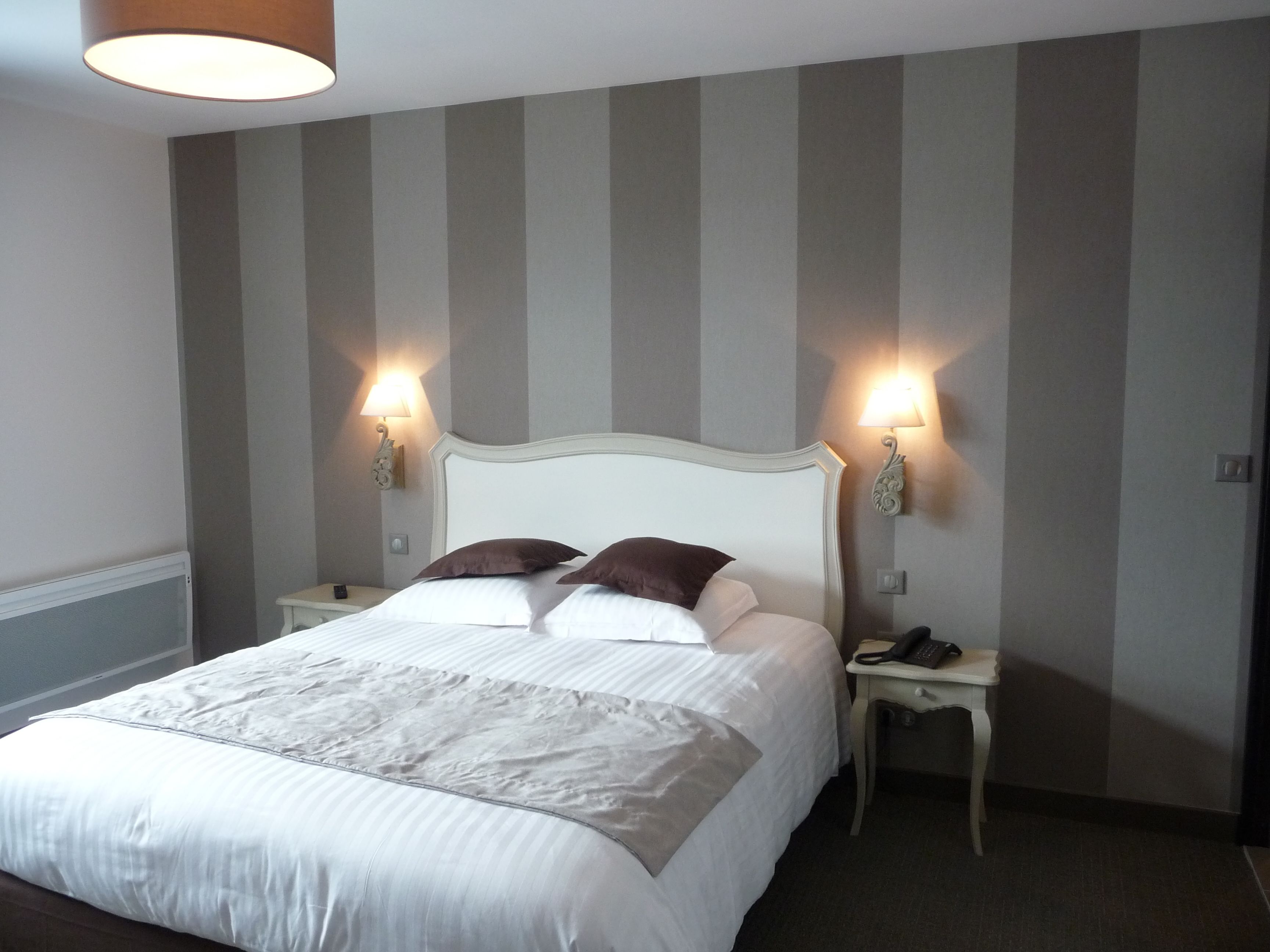A neatly made bed with a white headboard and two bedside tables, each with a lamp.