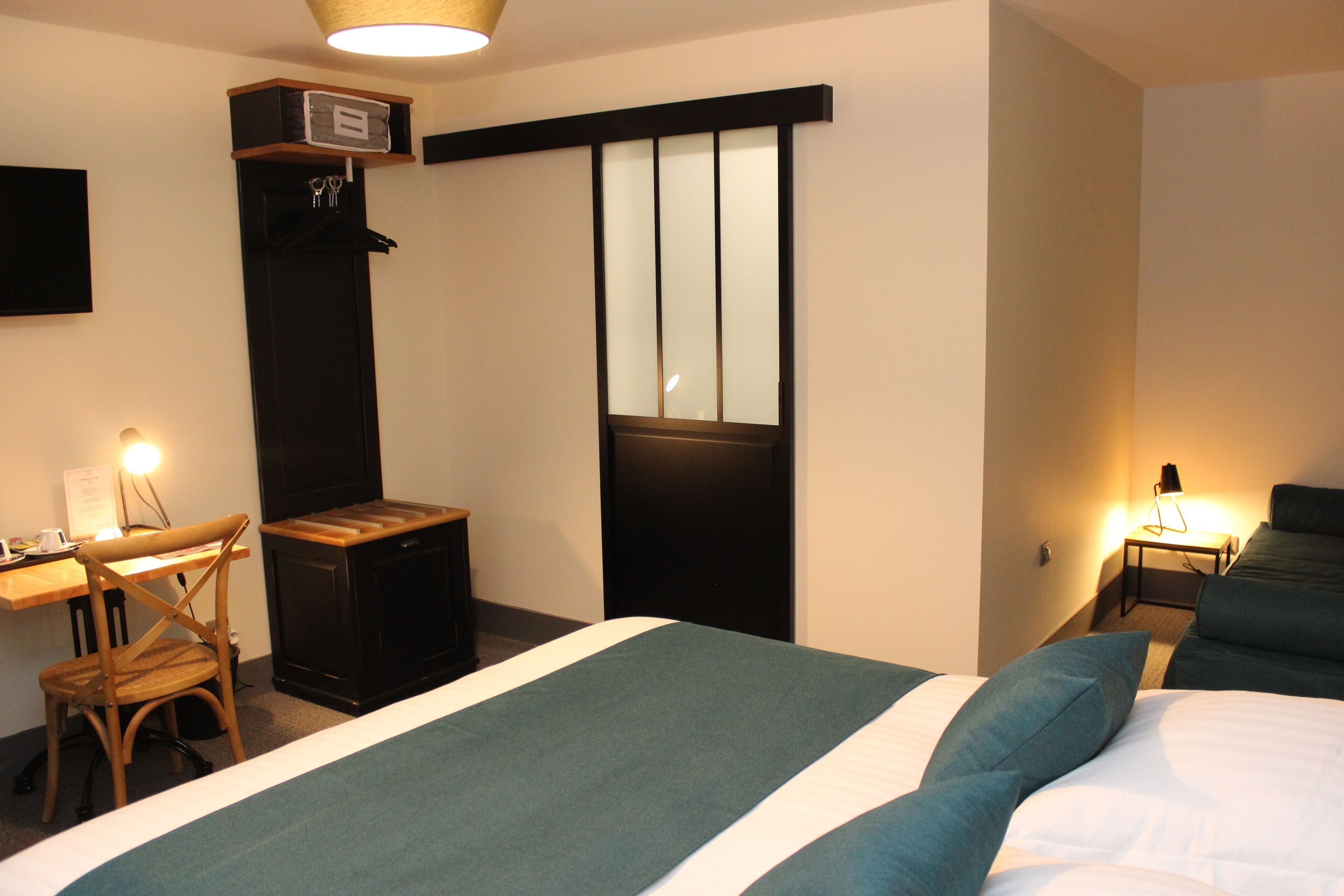 Una habitación de hotel con cama, escritorio, silla y un pequeño armario.