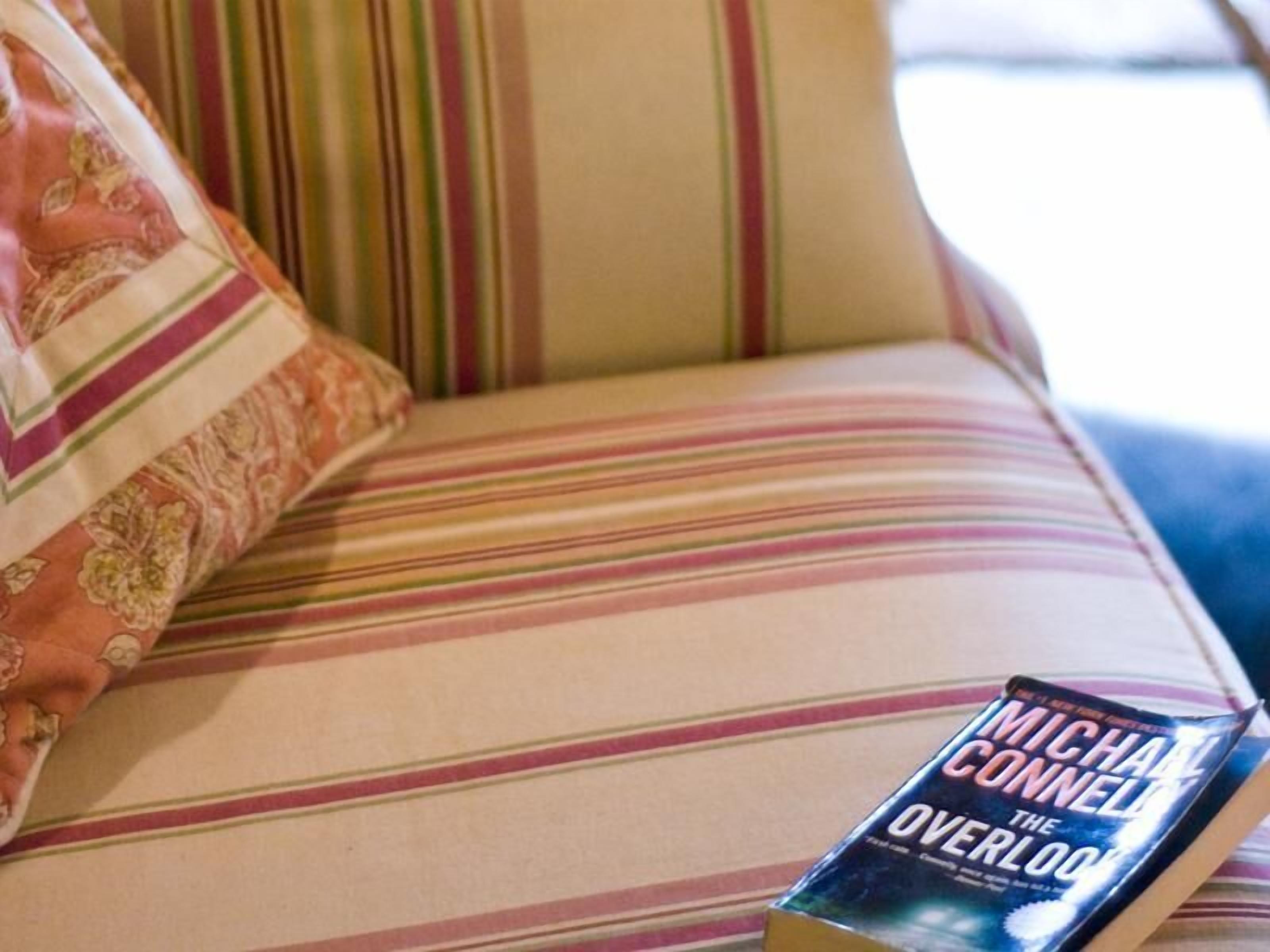 Ein gestreiftes Sofa mit einem Buch mit dem Titel „The Overlook“ von Michael Connelly.