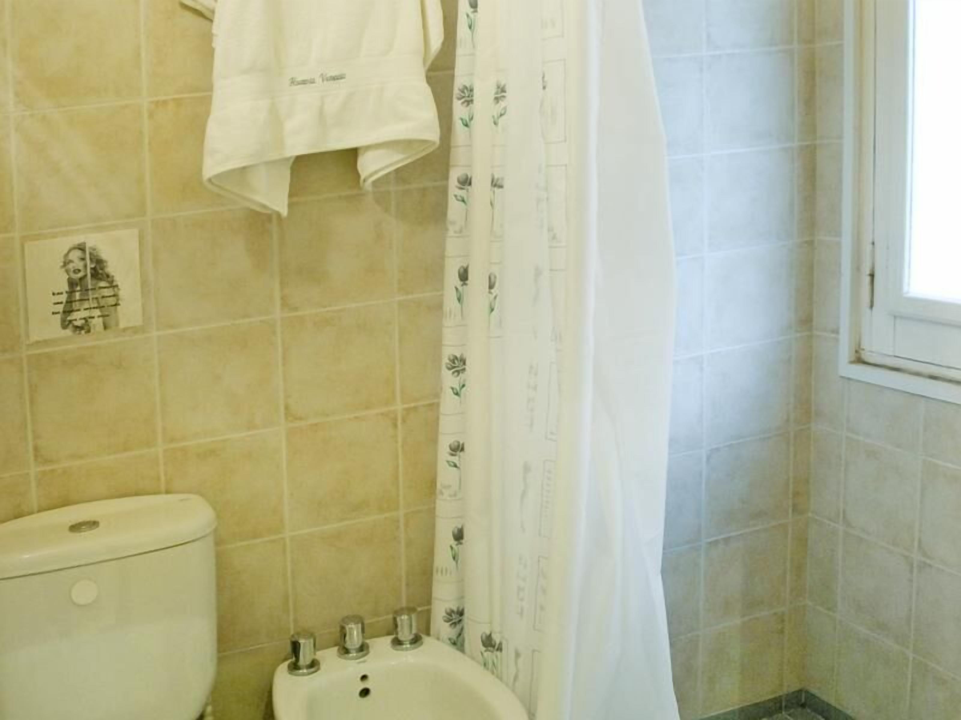 A bathroom with a toilet, bidet, and a shower curtain with floral patterns.