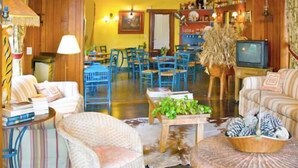 Una sala de estar acogedora con un sofá, sillones, una mesita de centro y un televisor.