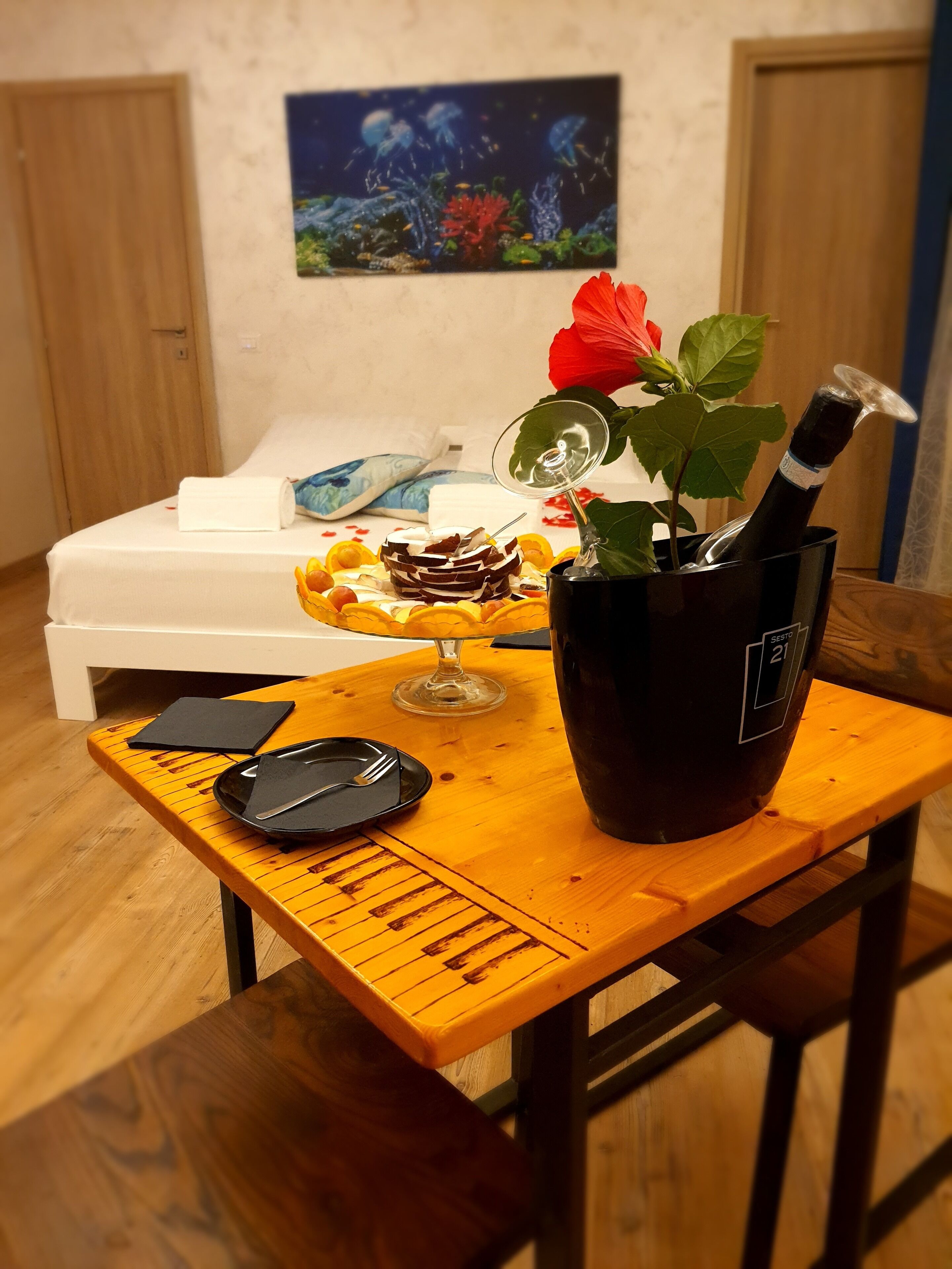 Ein Esstisch mit einer Weinflasche, Dessert und einer Blume in einer Vase.