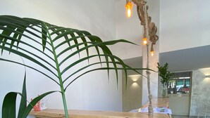Una recepción con detalles de madera, rodeada de grandes plantas verdes.