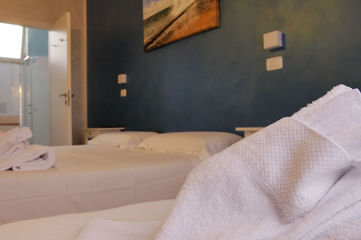 A hotel room with two beds, a bathroom, and a painting on the wall.