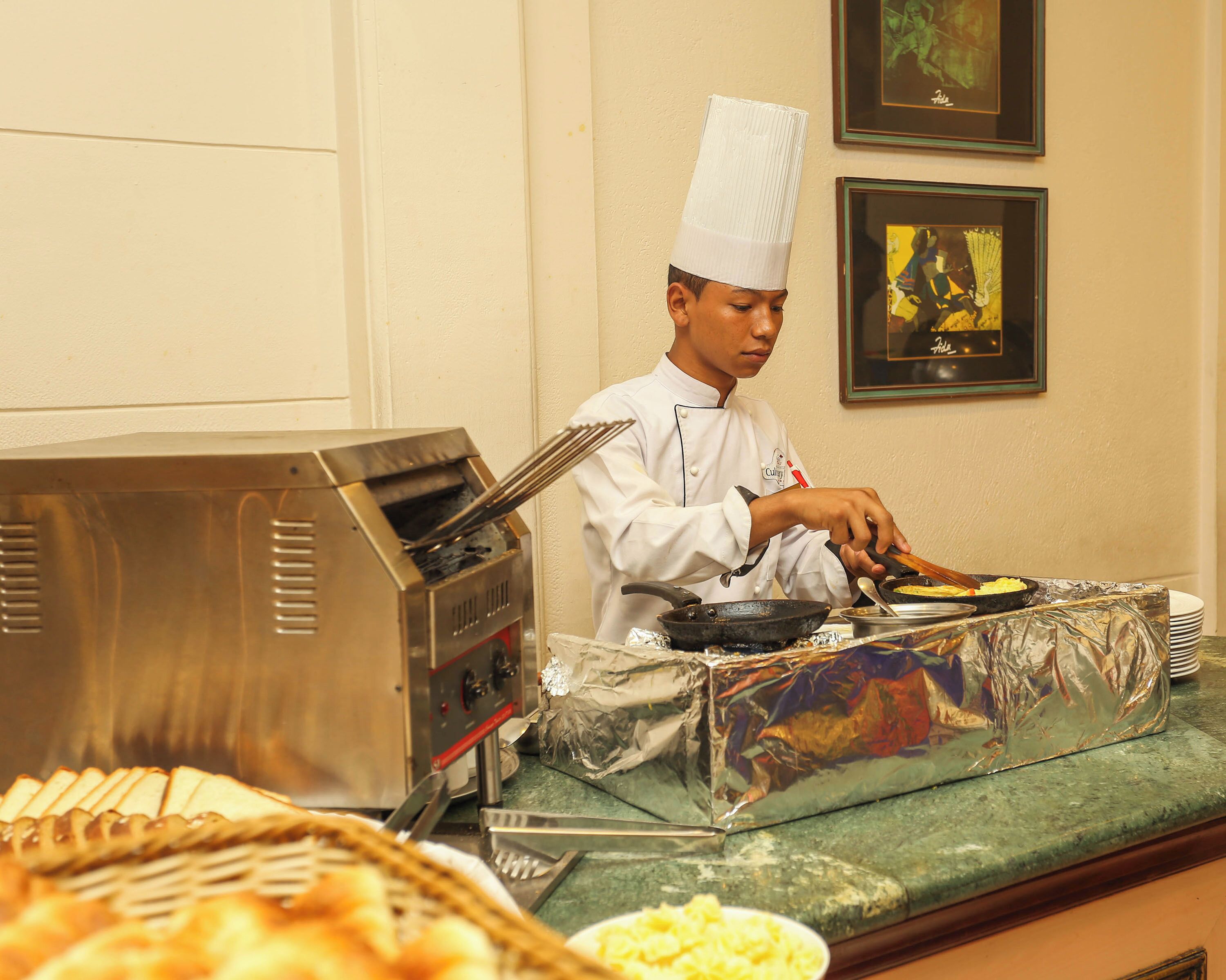 Un chef preparando comida en una cocina con espacio tipo bufé.