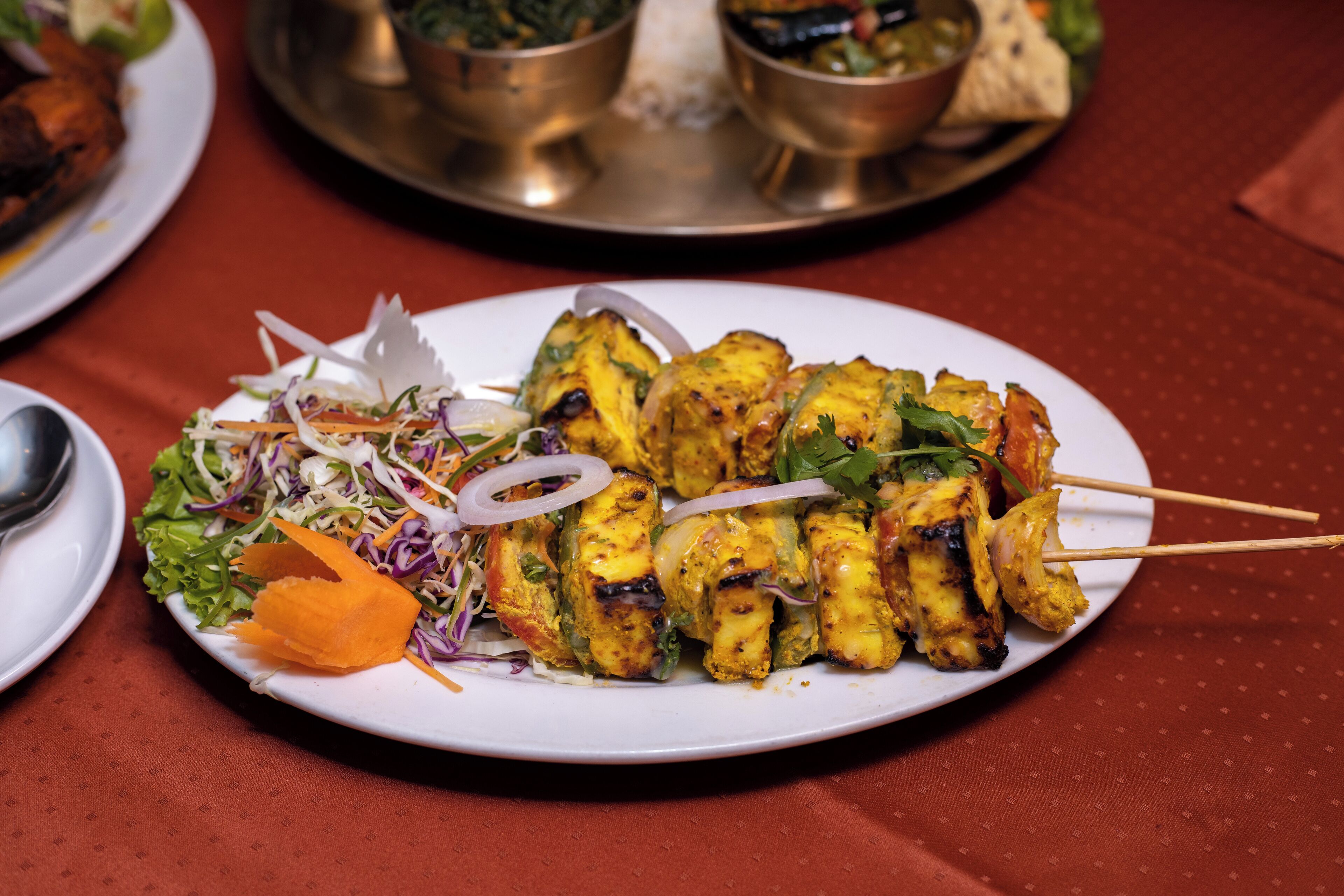 A plate of grilled chicken skewers with vegetables and a side salad.