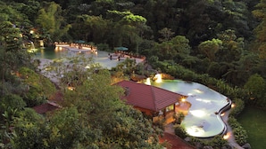A resort with a large pool, outdoor seating, and lush greenery.