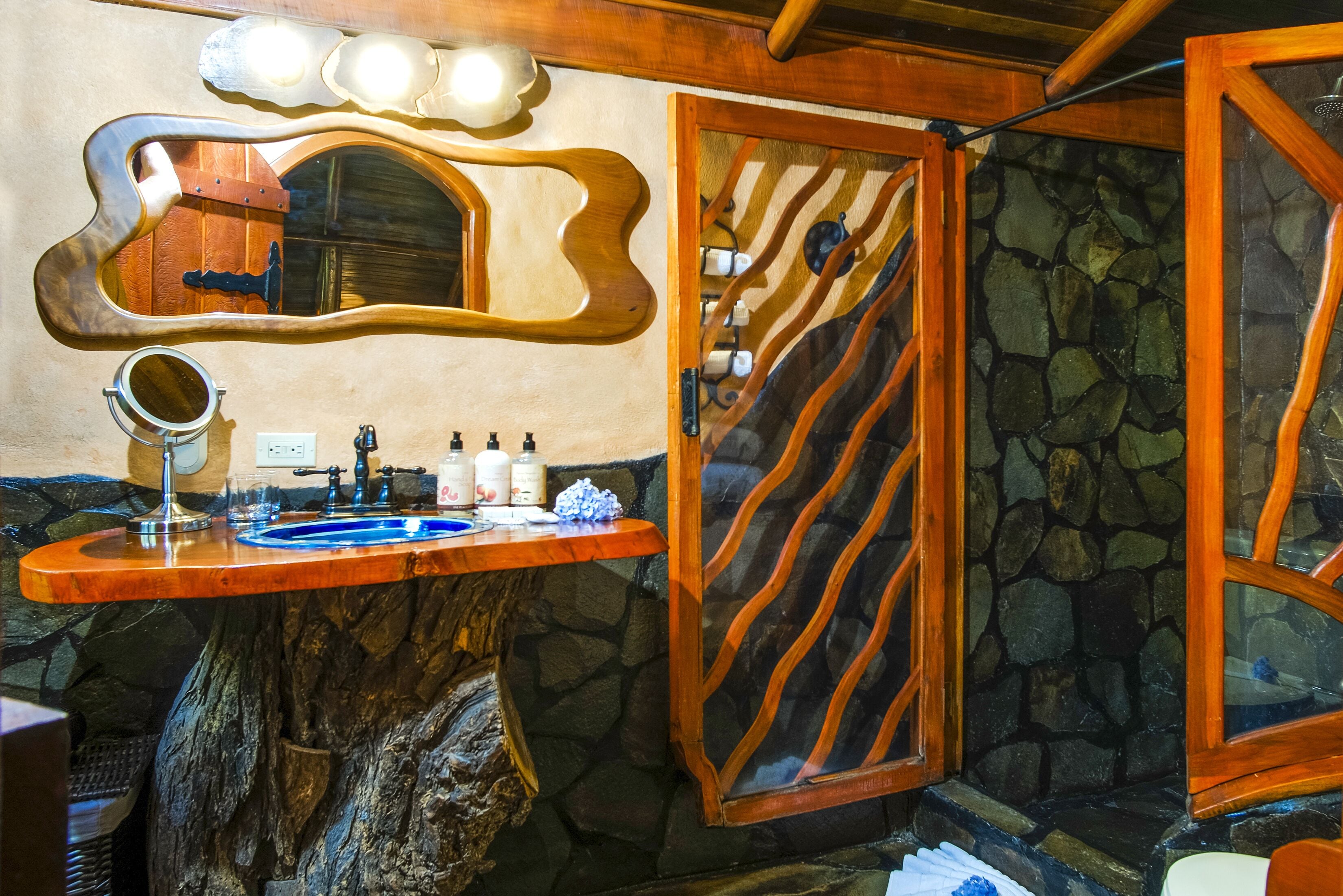 A bathroom with a wooden vanity, a mirror, and a stone wall.