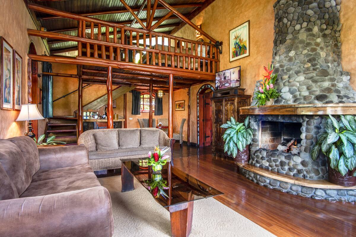 A spacious living area with a wooden staircase, a fireplace, and comfortable seating.