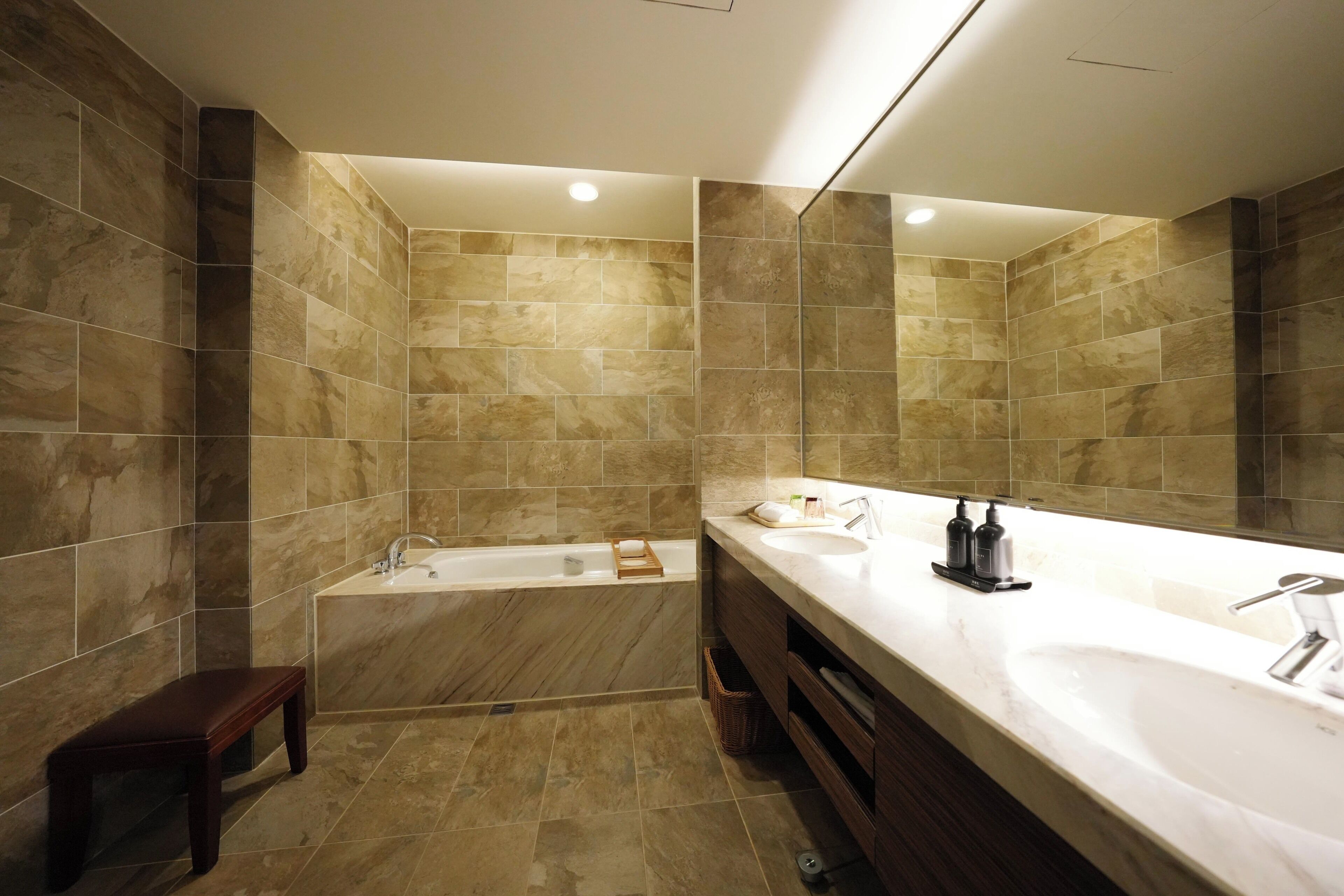 A modern bathroom with a bathtub, a large mirror, and a vanity with a sink.