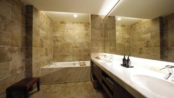 A modern bathroom with a bathtub, a large mirror, and a vanity with a sink.