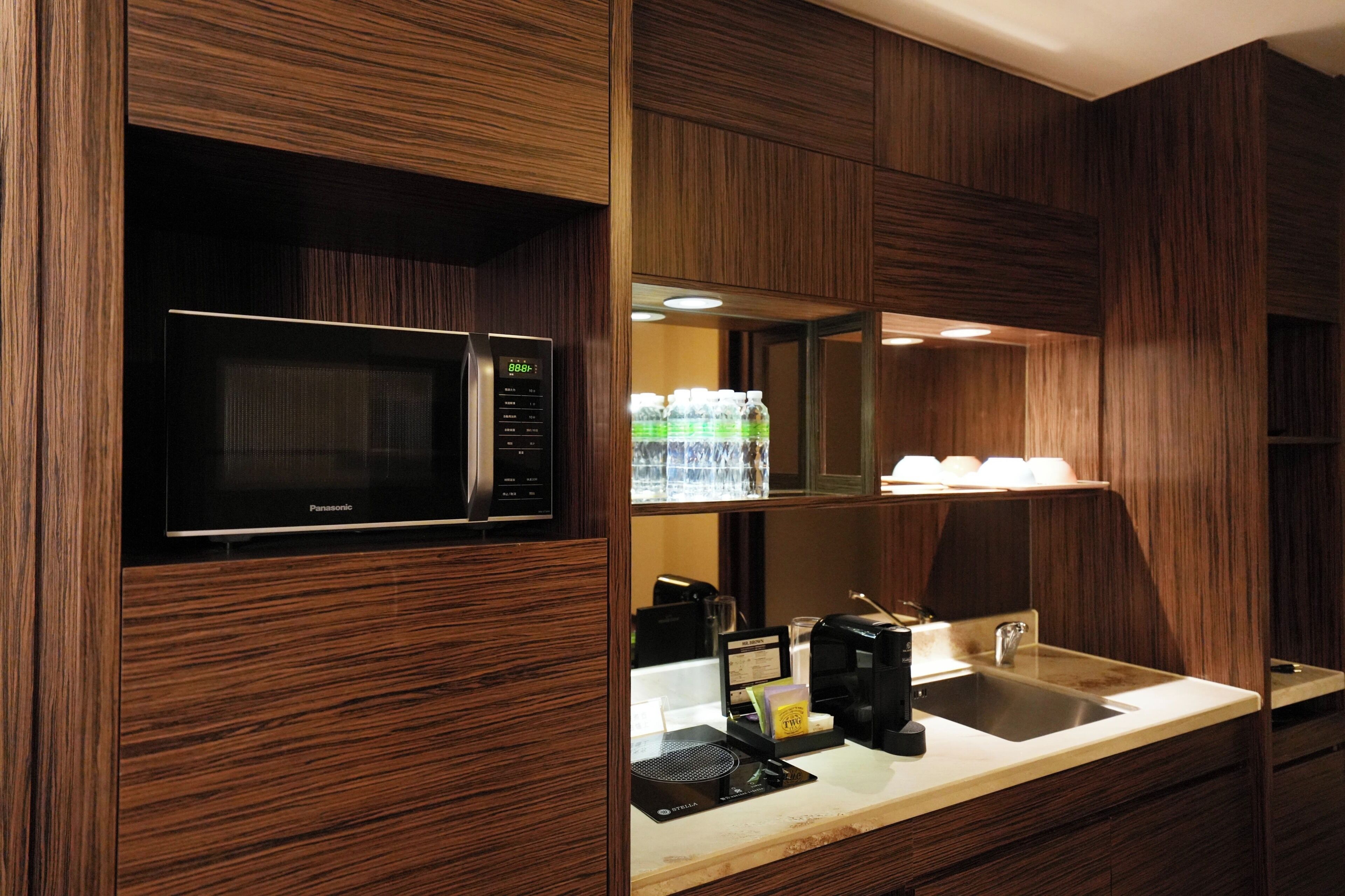 A modern kitchen with a built-in microwave, coffee maker, and a sink.