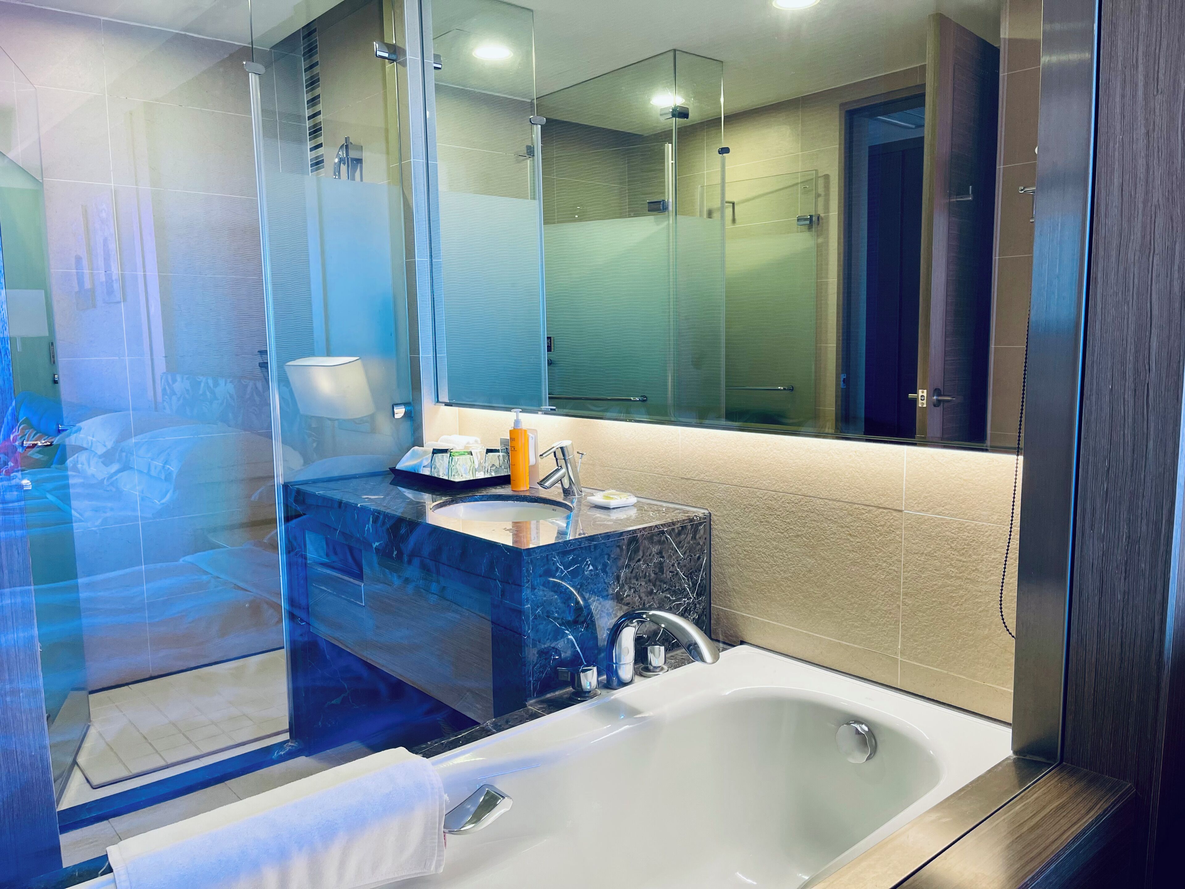 A modern bathroom with a glass shower enclosure, a marble sink, and a large mirror.