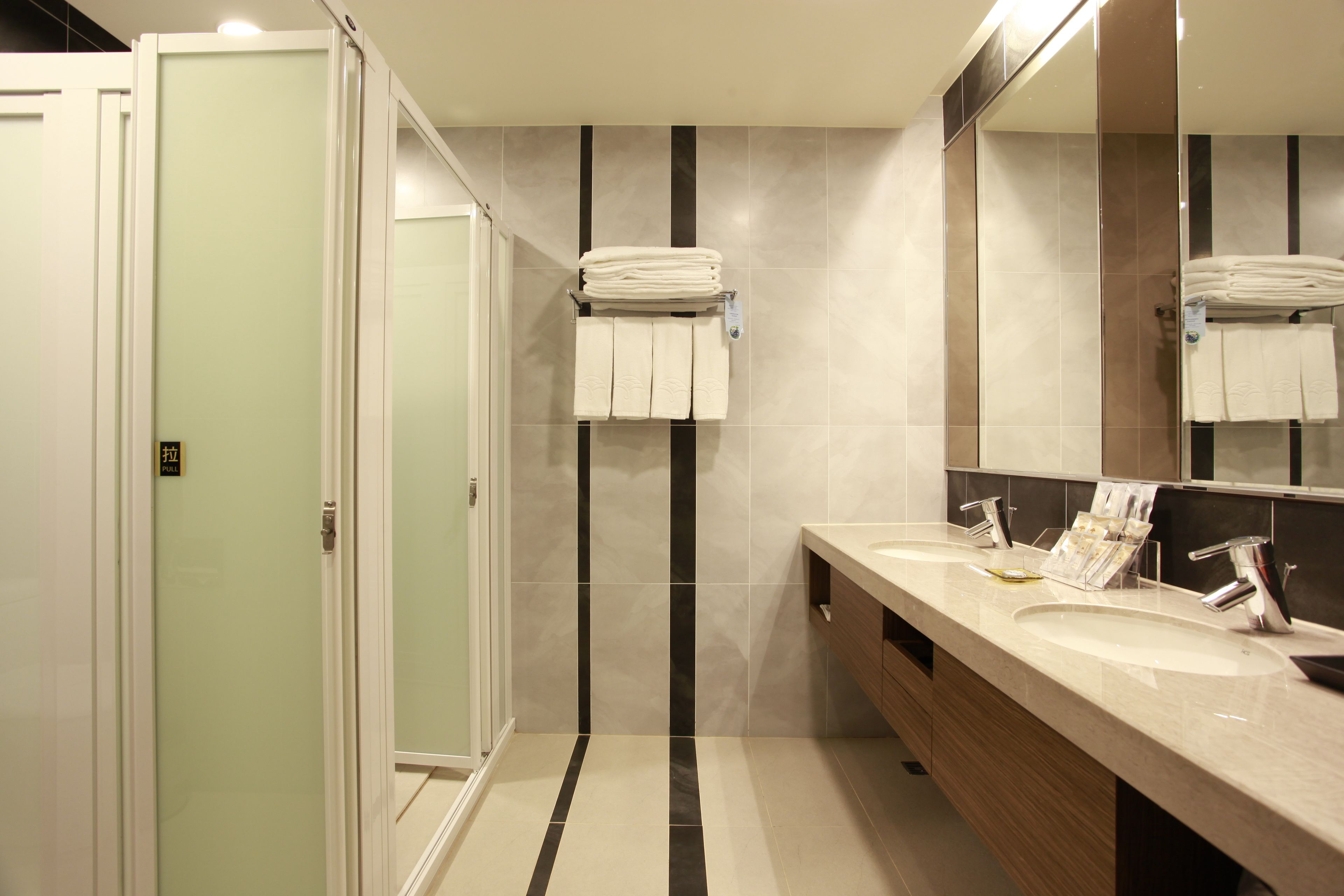 A modern bathroom with a dual sink vanity, a large mirror, and a towel rack.