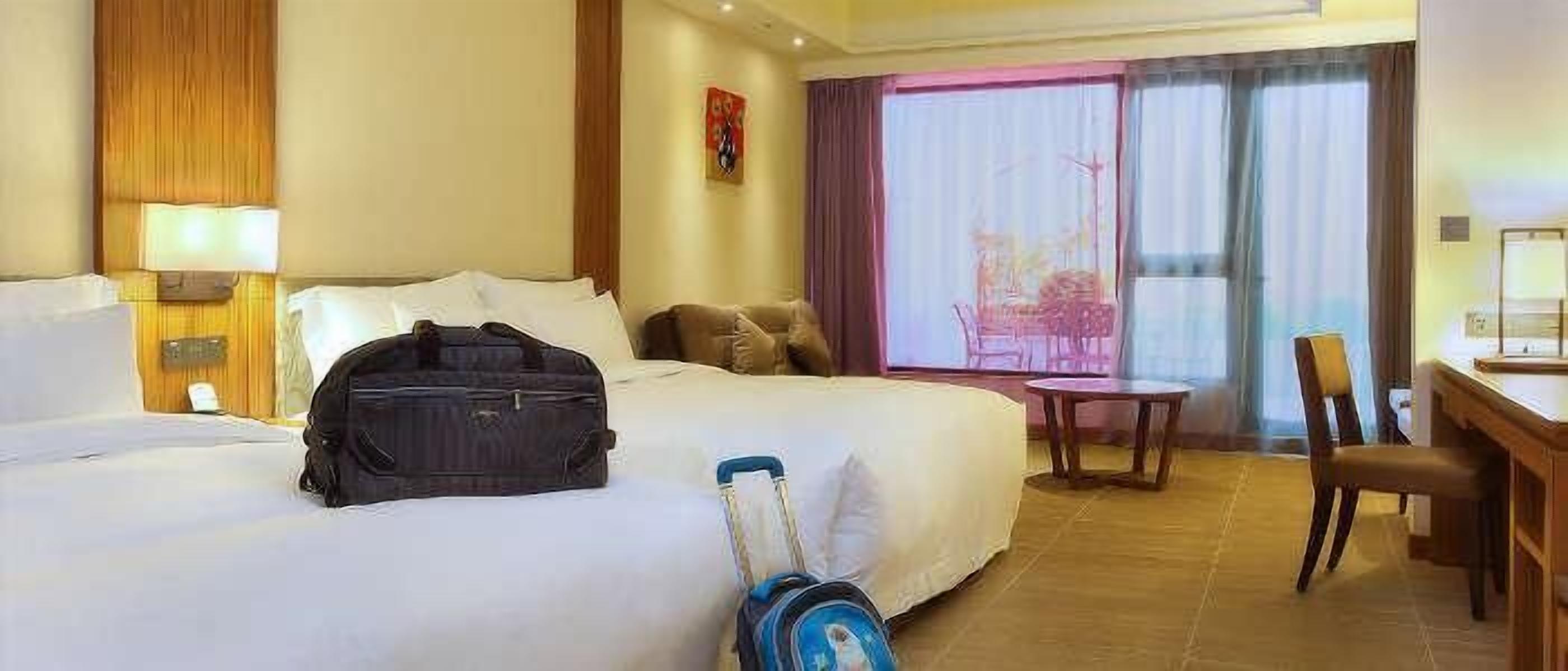 Una habitación de hotel con una cama, un escritorio, una silla y una maleta.