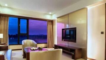 A hotel room with a large window, a flat-screen TV, a desk, and a bed.