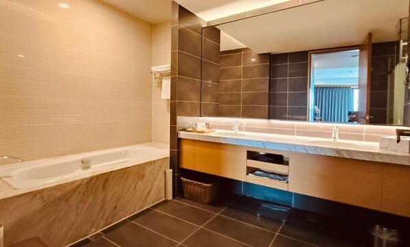 A modern bathroom with a bathtub, a large mirror, and a vanity with a countertop.