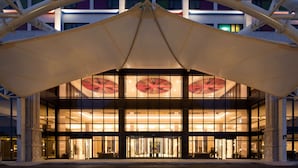 A modern hotel entrance with a large canopy and glass facade.