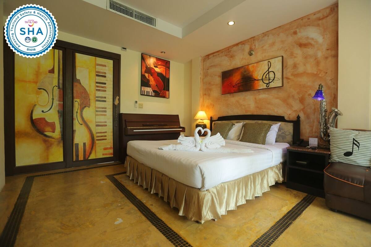A hotel room with a large bed, a nightstand, a lamp, and artwork on the walls.