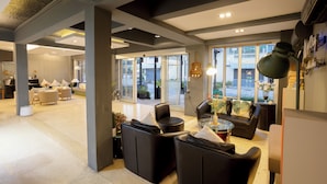 Eine großzügige Lobby mit modernem Design, ausgestattet mit einer Sitzecke mit Sofas und Sesseln, einem Couchtisch und einem großen Fenster mit Blick nach außen.
