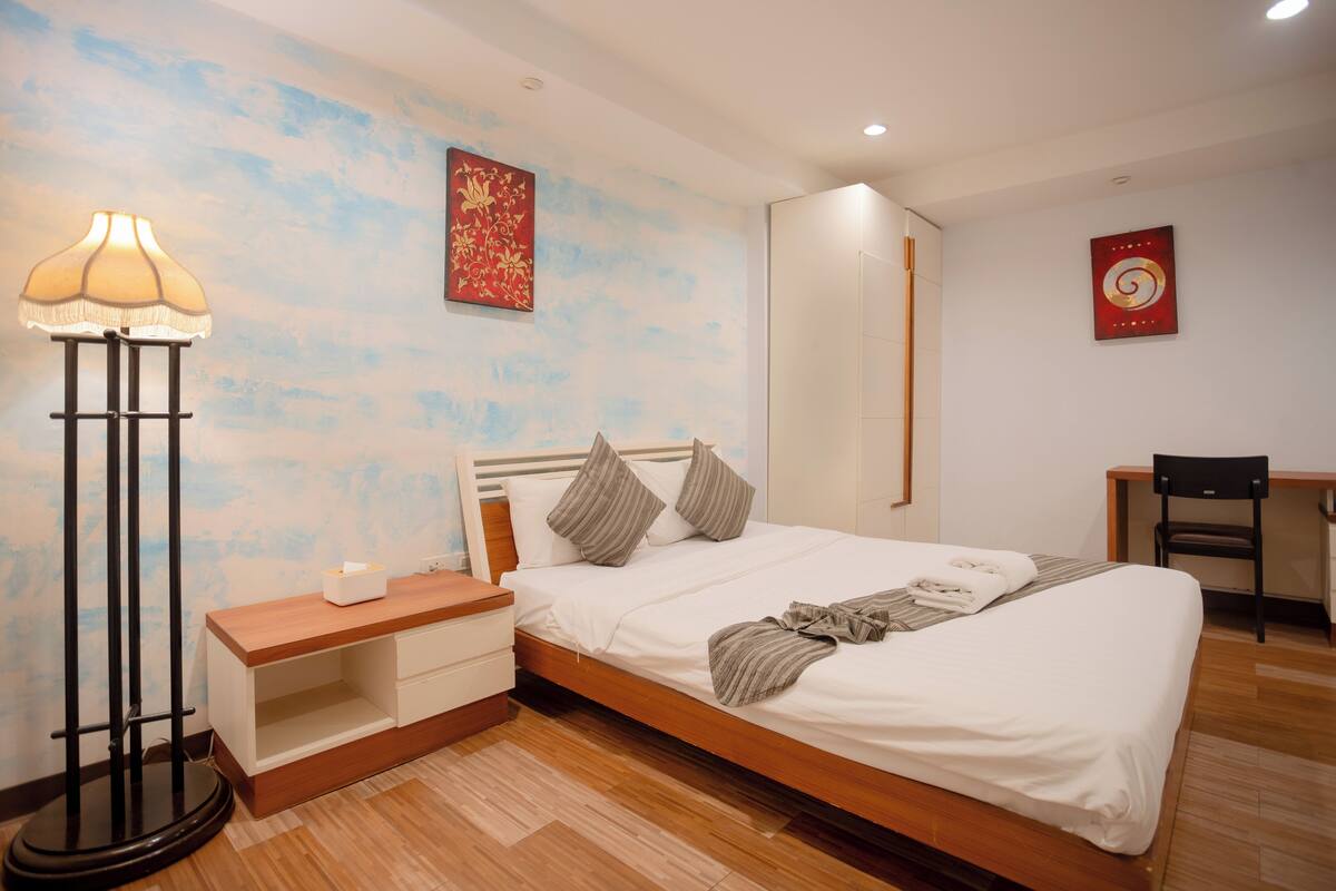 A neatly arranged bedroom with a wooden bed, bedside table, and a floor lamp.