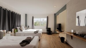 Ein Hotelzimmer mit zwei Betten, einem Fernseher, einem kleinen Tisch und einem Fenster mit Vorhängen.