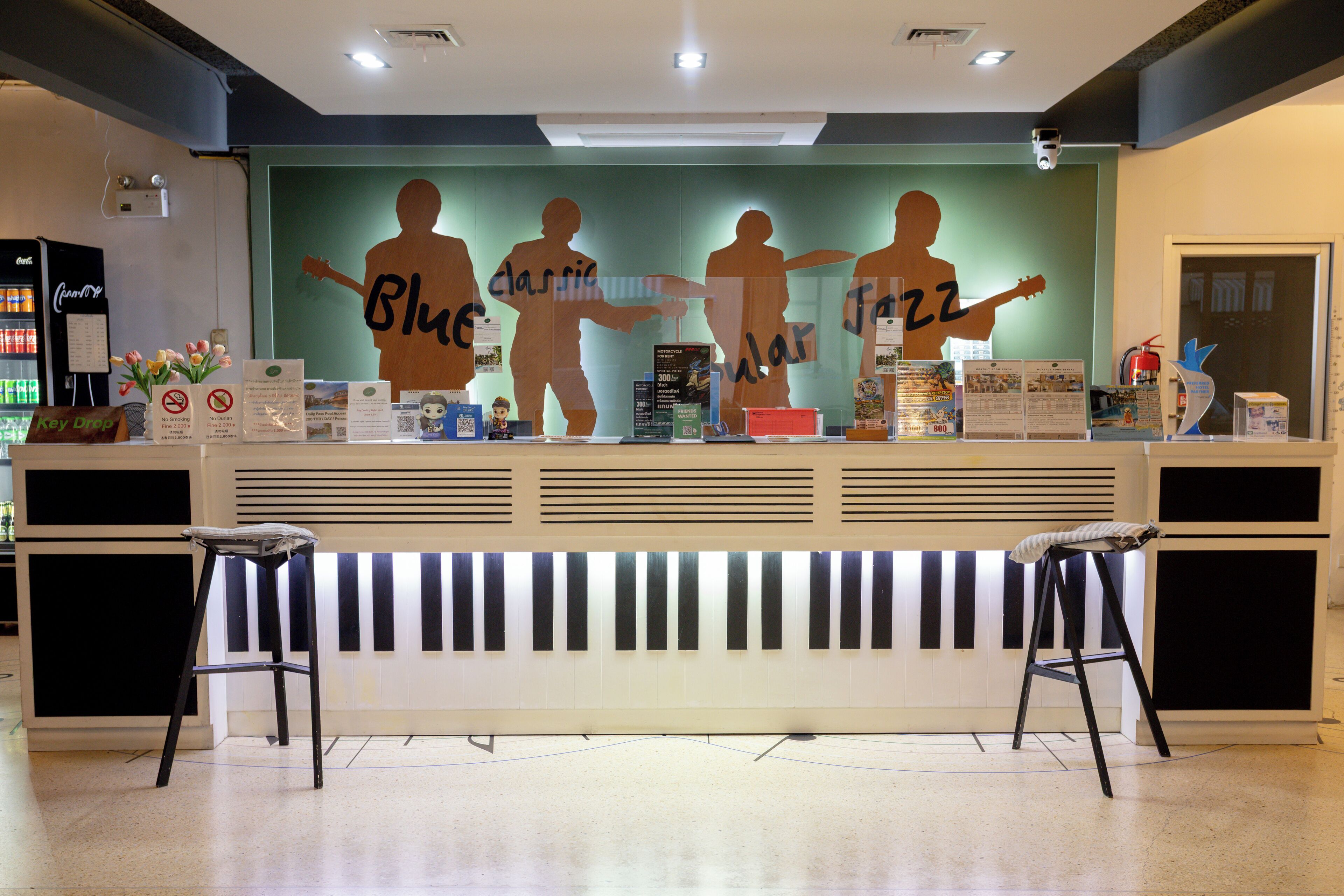 A reception area with a counter, two stools, and a wall with silhouettes of people playing musical instruments.