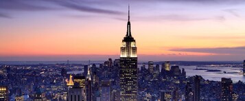 Een stadsgezicht met een opvallend wolkenkrabben, waarschijnlijk het Empire State Building, in de schemering.