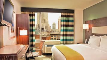 A hotel room with a bed, desk, chair, and a television.