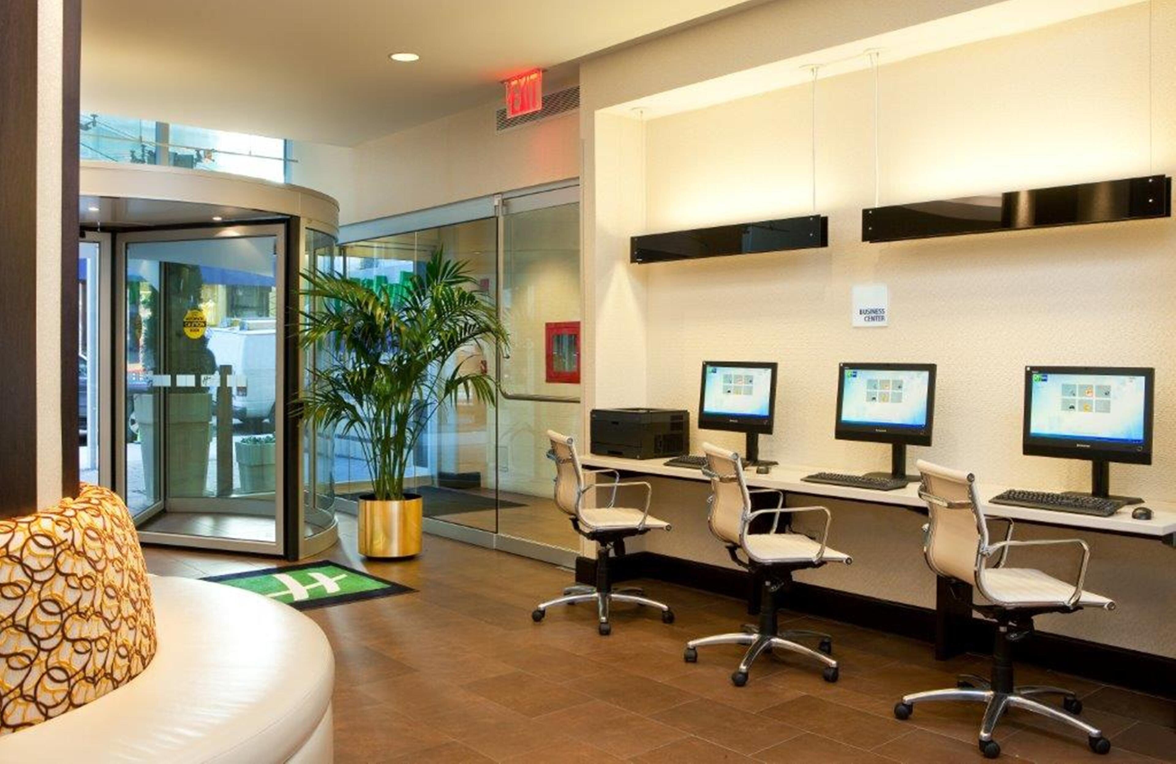 A modern office space with a reception area, a glass door entrance, and multiple computer workstations.