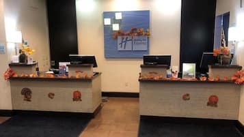 A Holiday Inn Express reception area with two reception desks, a large sign above, and a dark carpeted floor.