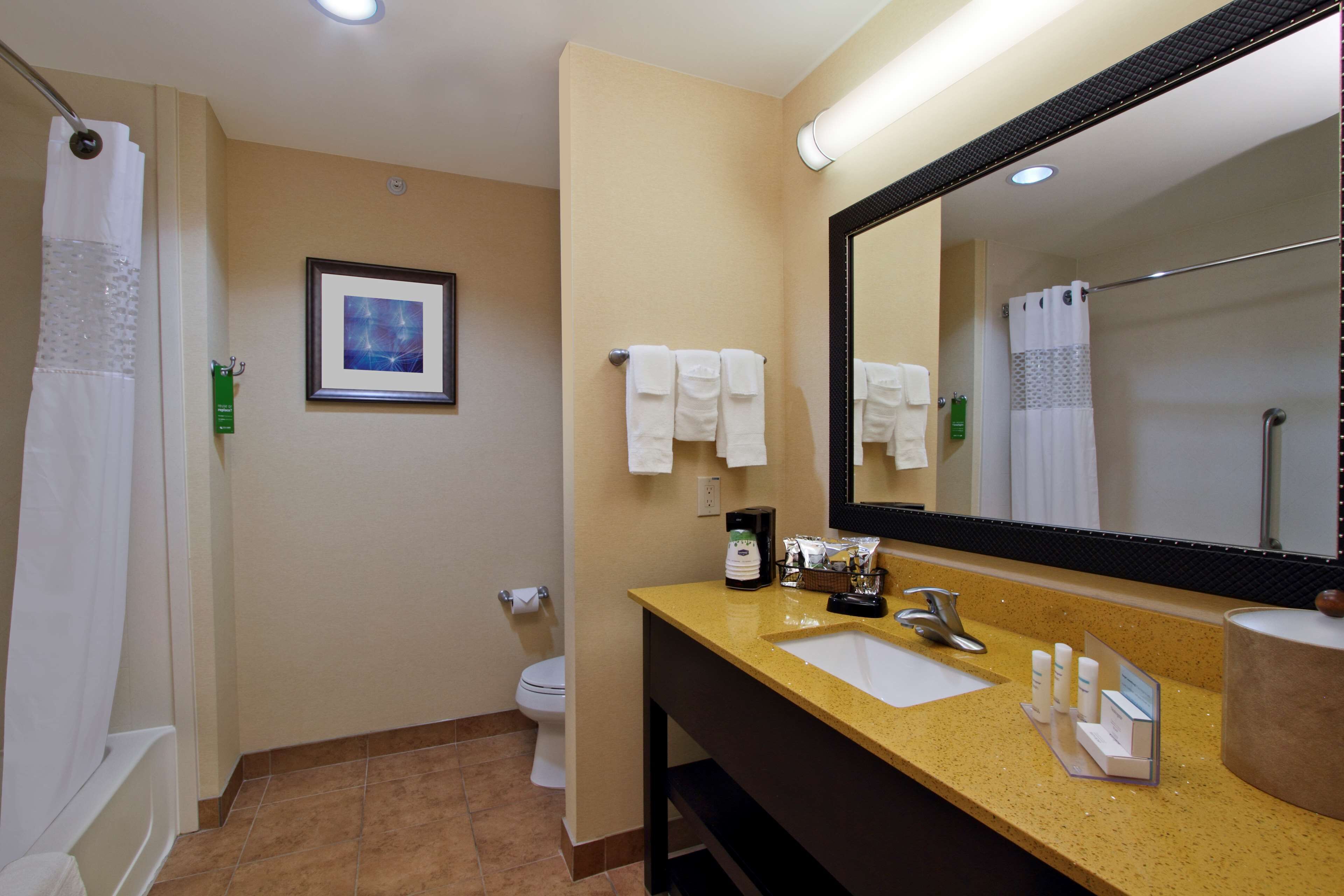 Un baño de hotel con lavamanos, espejo y perchero para toallas.
