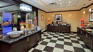 A hotel kitchen with a checkered floor, buffet setup, and various food items.
