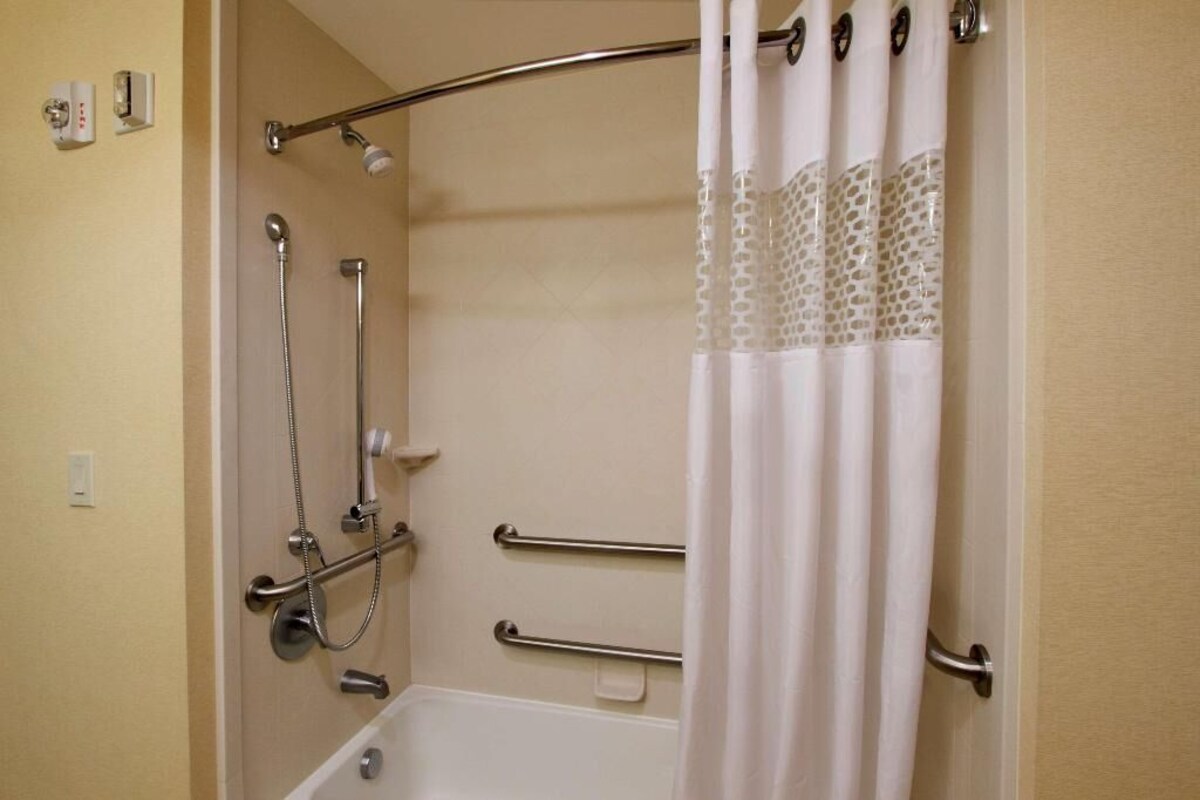 A shower area with a bathtub, grab bars, and a showerhead.