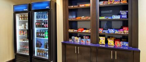 Dos dispensadores refrigerados para bebidas y un expositor para aperitivos en el vestíbulo de un hotel.