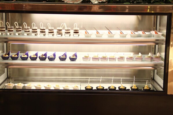 A dessert display case with multiple shelves containing various desserts. - Ramada Longyan (Longyan)