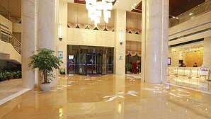 A spacious lobby with marble flooring, large columns, and a reception area.