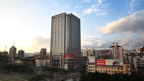 A high-rise building with multiple floors, surrounded by other buildings and a river.