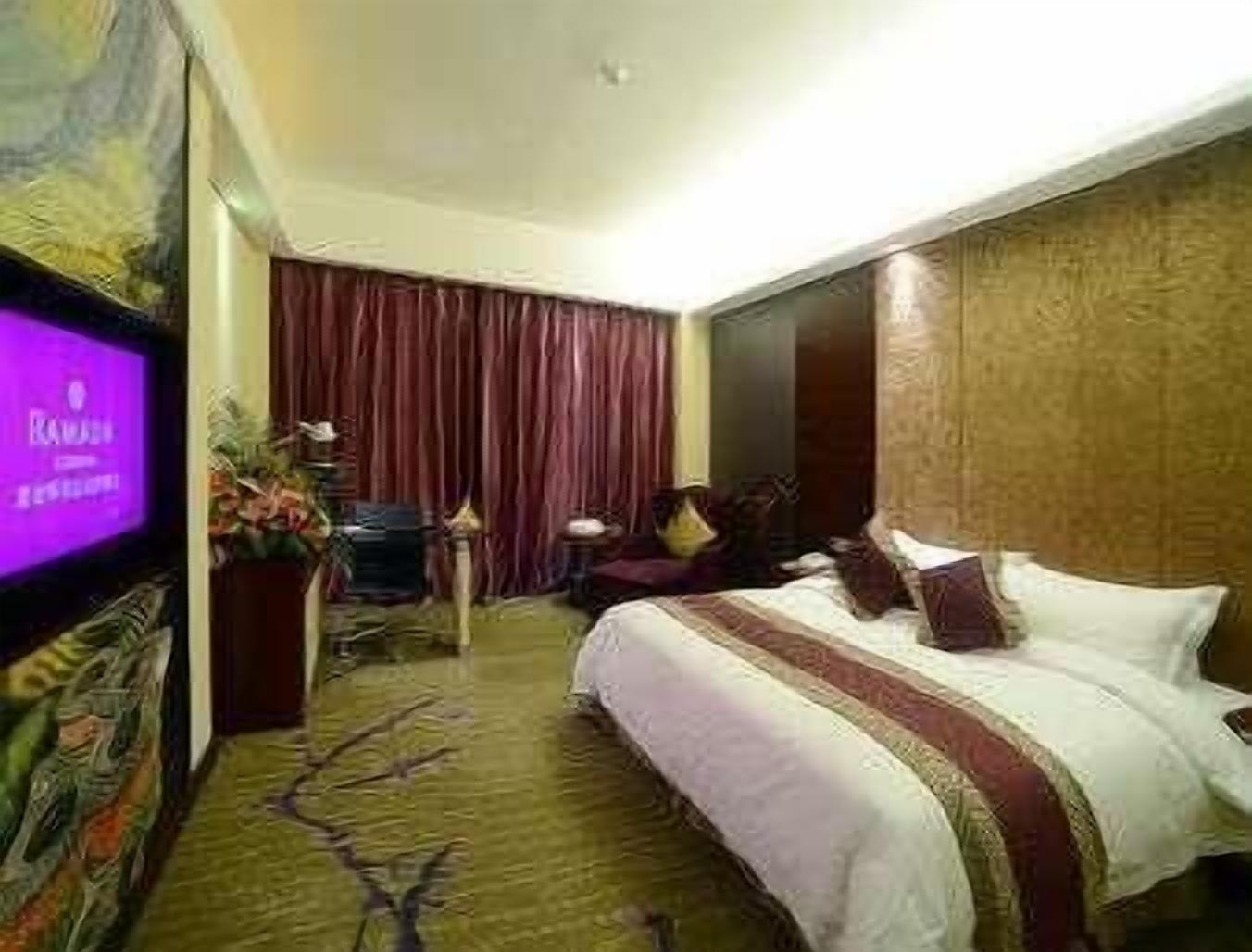 Habitación de hotel con cama, televisión, escritorio y cortina.