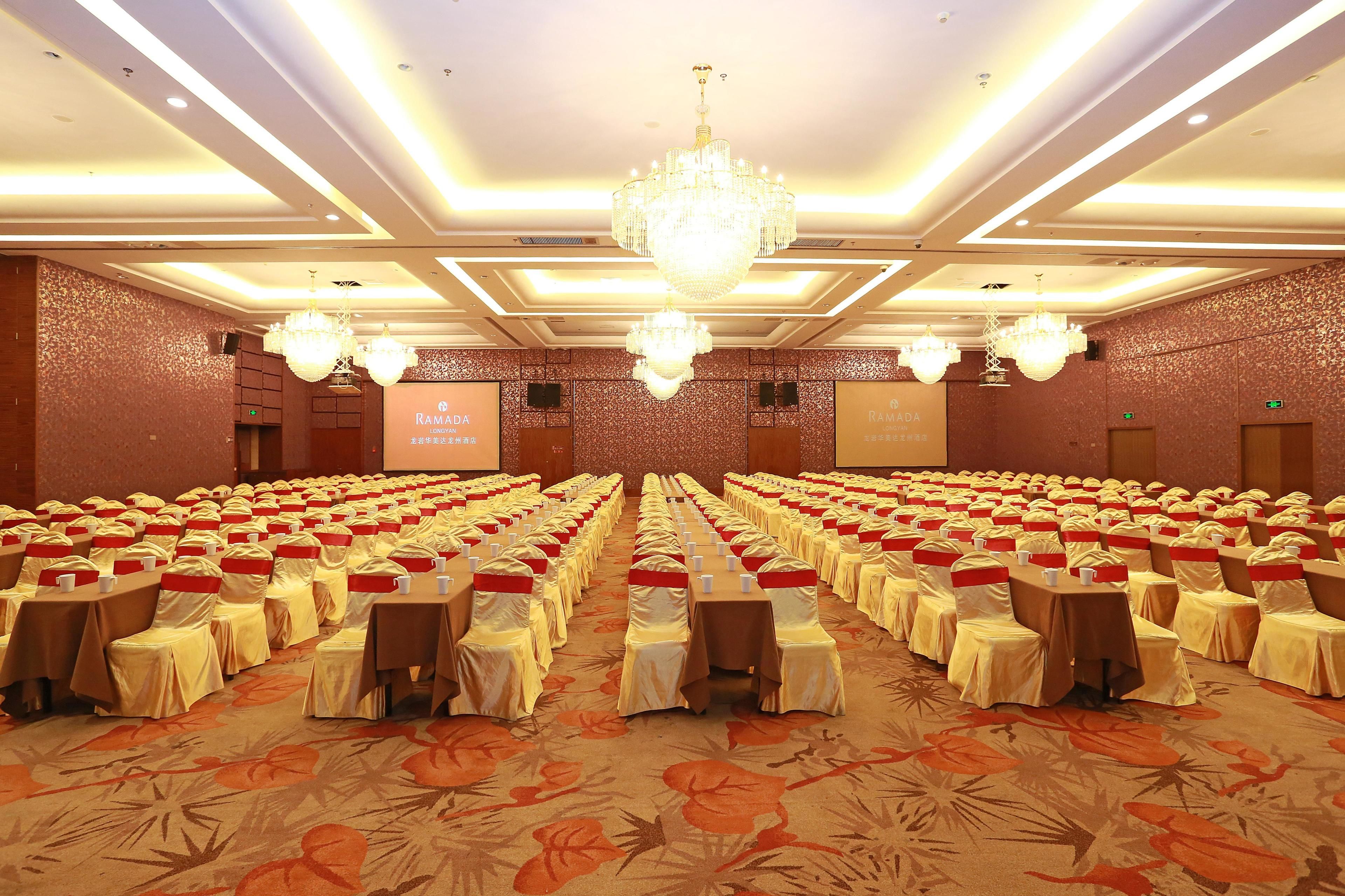 A conference room with rows of tables, chairs, and a large chandelier.