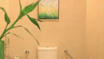 A bathroom with a toilet, grab bars, a trash bin, and a painting on the wall.