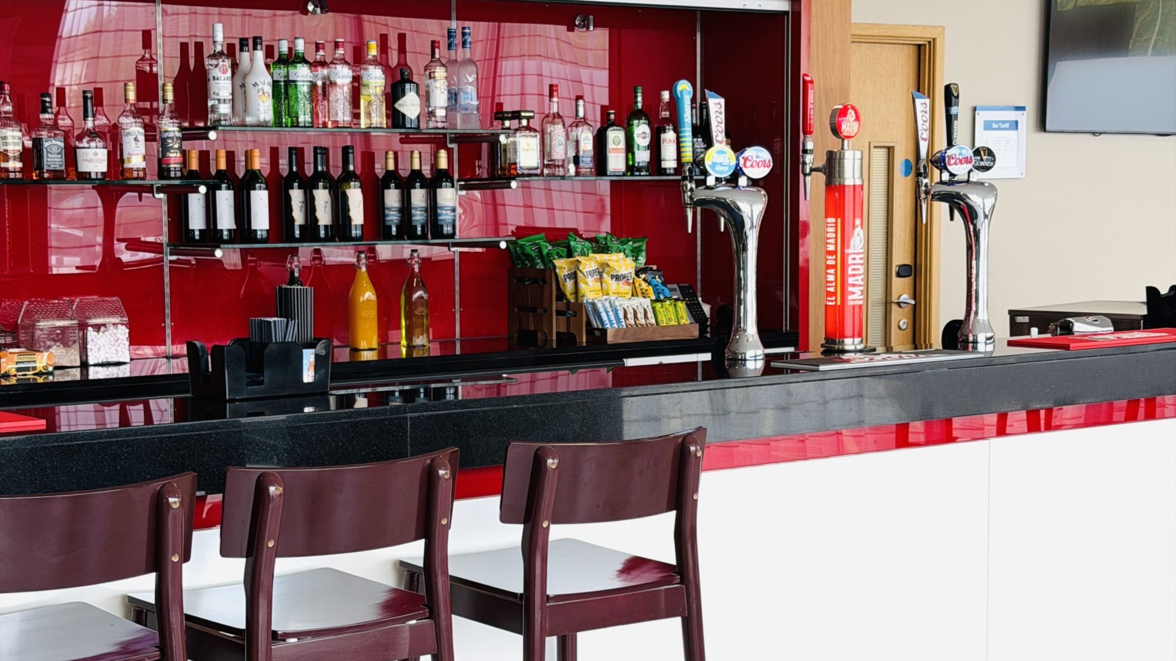 A bar area with multiple liquor bottles, a beer tap, and snack bags.
