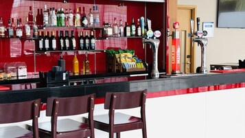 A bar area with multiple liquor bottles, a beer tap, and snack bags.