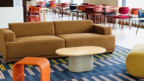 A modern lounge area with a sofa, a small table, and colorful chairs.