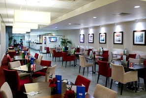 A hotel dining area with multiple tables and chairs, a television screen, and framed artwork on the walls. - Holiday Inn Express Rotherham North by IHG (Rotherham)